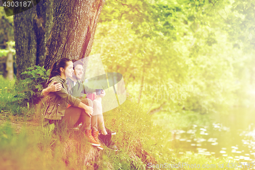 Image of happy couple with cups drinking tea in nature