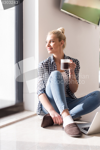 Image of young woman drinking coffee enjoying relaxing lifestyle