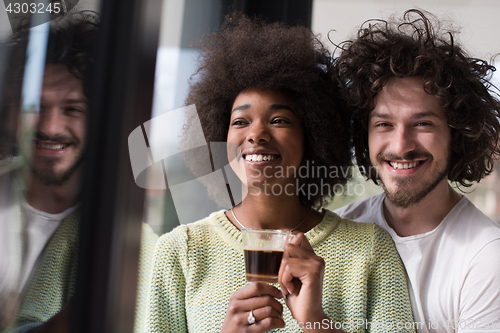 Image of happy multiethnic couple relaxing at modern home indoors