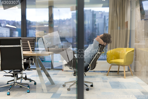 Image of young businessman relaxing at the desk