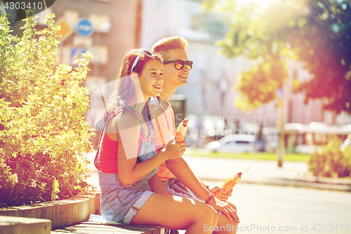 Image of happy teenage couple eating hot dogs in city