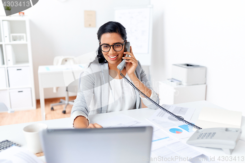 Image of businesswoman calling on desk phone at office