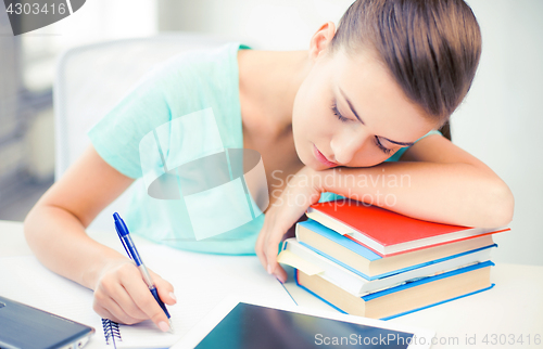 Image of tired student sleeping on stock of books