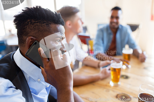 Image of man calling on smartphone and drinking beer at bar