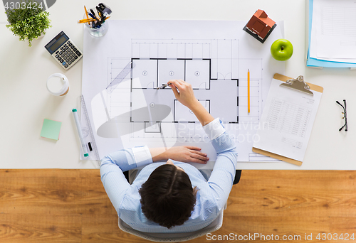 Image of architect with compass measuring blueprint