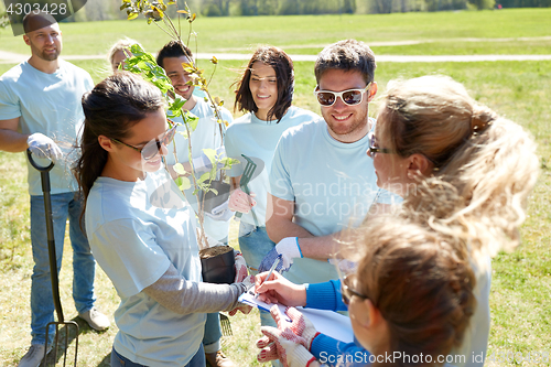 Image of group of volunteers with tree seedlings in park