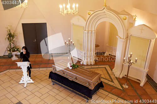 Image of crying woman near coffin at funeral in church