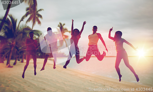 Image of happy friends dancing and jumping on beach