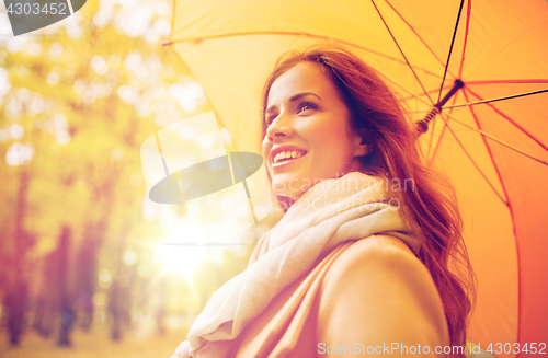 Image of happy woman with umbrella walking in autumn park