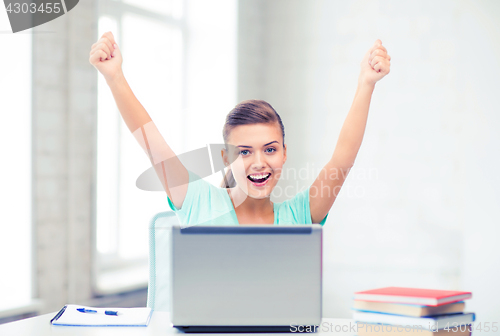 Image of happy student girl with laptop at school