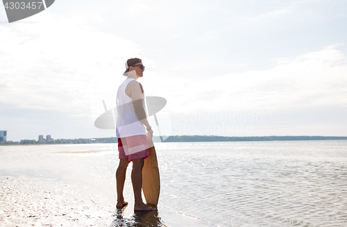 Image of happy young man with skimboard on summer beach