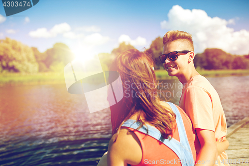 Image of happy teenage couple sitting on river berth