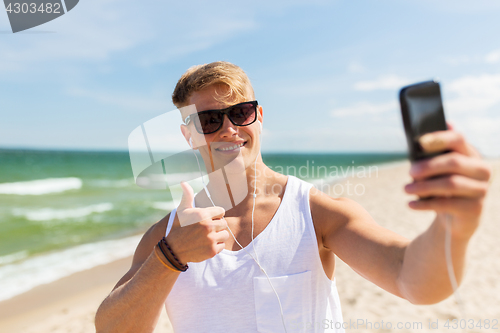 Image of man with smartphone taking selfie on summer beach