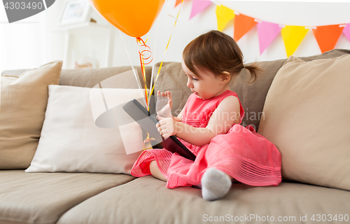 Image of baby girl with tablet pc on birthday party at home