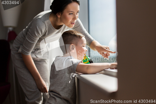 Image of mother and son looking through window at home