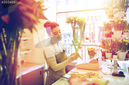 Image of smiling florist woman making bunch at flower shop