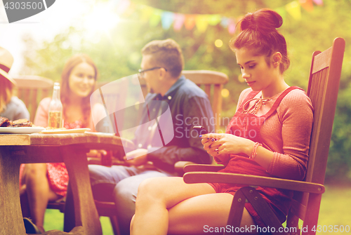 Image of woman with smartphone and friends at summer party