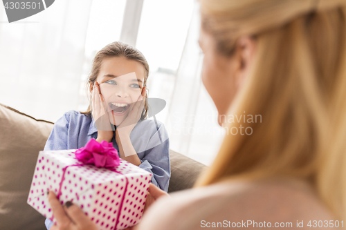 Image of mother giving birthday present to girl at home