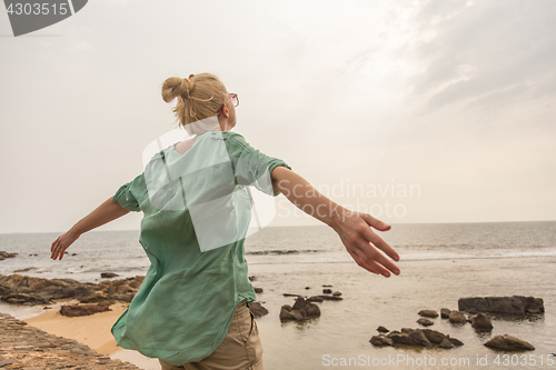 Image of Free woman enjoying windy weather on beach on overcast day