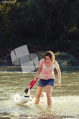 Image of Woman playing with dog in water