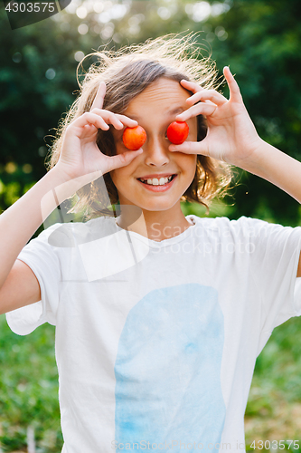 Image of Cheerful girl playing with plums