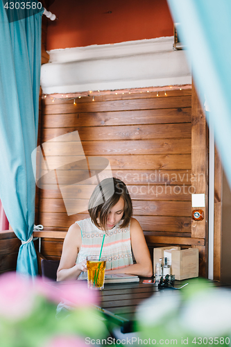 Image of Girl in cafe with drink and tablet