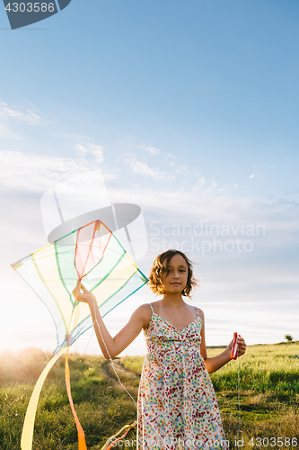 Image of Girl holding kite and running in field