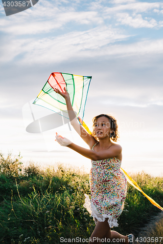 Image of Girl holding kite and running in field