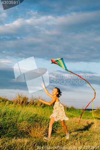 Image of Cheerful girl running with kite