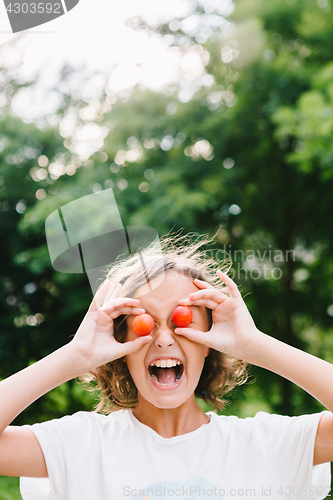 Image of Cheerful girl playing with plums