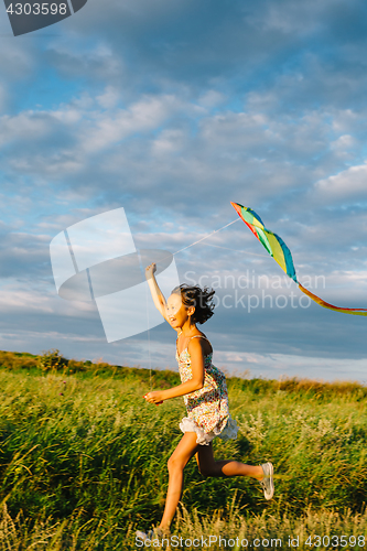 Image of Cheerful girl running with kite