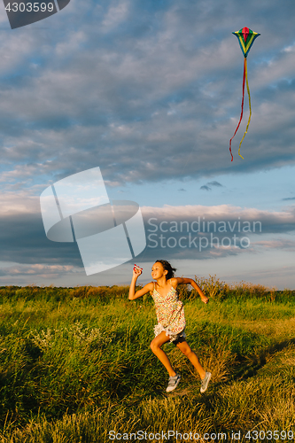 Image of Cheerful girl running with kite