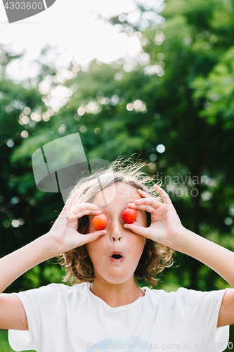 Image of Cheerful girl playing with plums