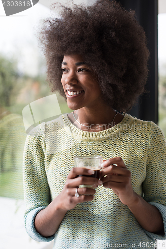 Image of African American woman drinking coffee looking out the window