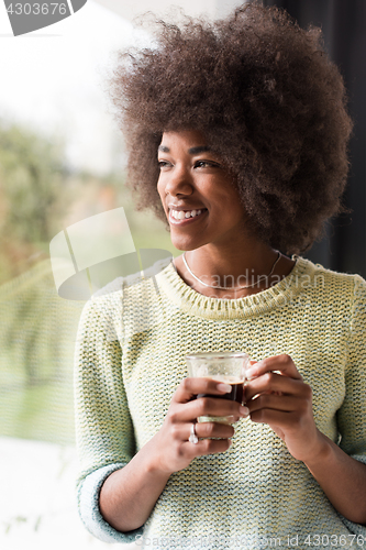 Image of African American woman drinking coffee looking out the window