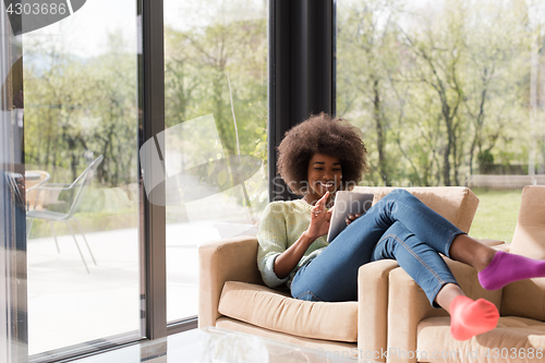 Image of young african american woman at home using digital tablet