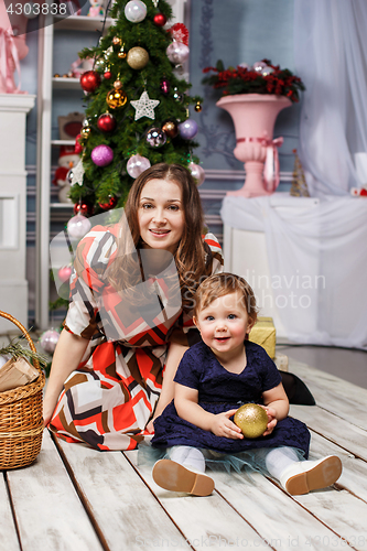 Image of Little girl With her happy mother at studio with christmas decorations