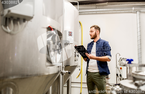 Image of man with clipboard at craft brewery or beer plant