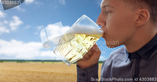 Image of close up of young man drinking beer from glass mug