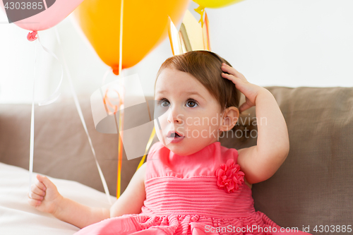 Image of happy baby girl in crown on birthday party at home