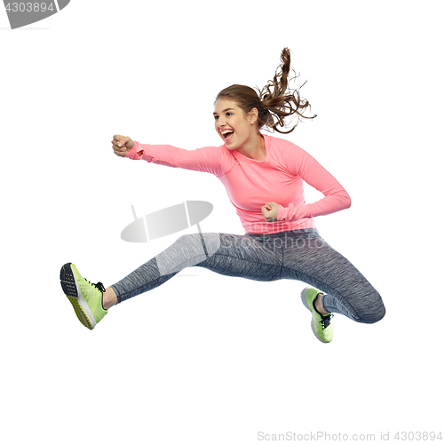 Image of happy sporty young woman jumping in fighting pose