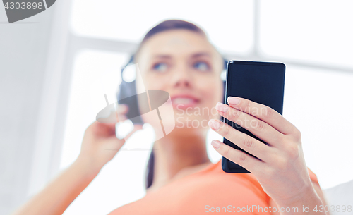 Image of woman with headphones and smartphone at home
