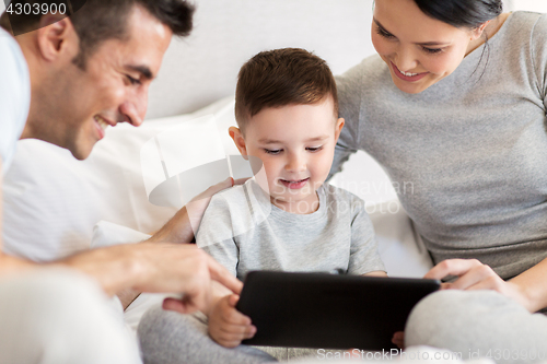 Image of happy family with tablet pc in bed at home