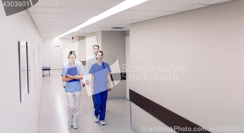 Image of group of medics or doctors walking along hospital