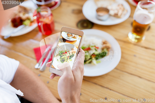 Image of hand with smartphone picturing food at restaurant