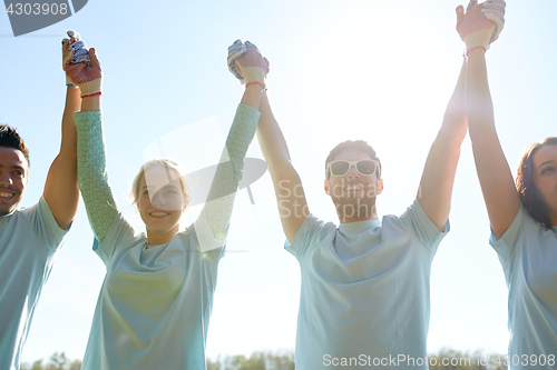 Image of group of happy volunteers holding hands outdoors