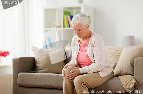 Image of senior woman suffering from pain in leg at home