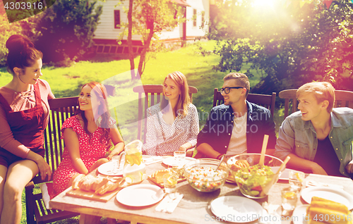 Image of happy friends having dinner at summer garden party