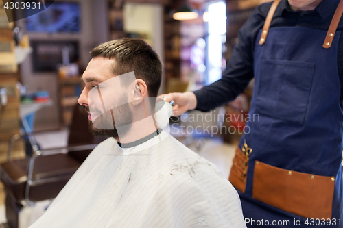 Image of barber with brush cleaning male neck at barbershop