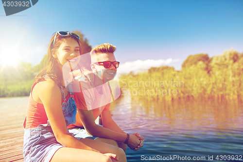 Image of happy teenage couple sitting on river berth